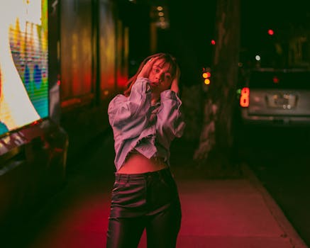 A fashionable woman in a denim jacket and black pants posing at night in Mexico City.