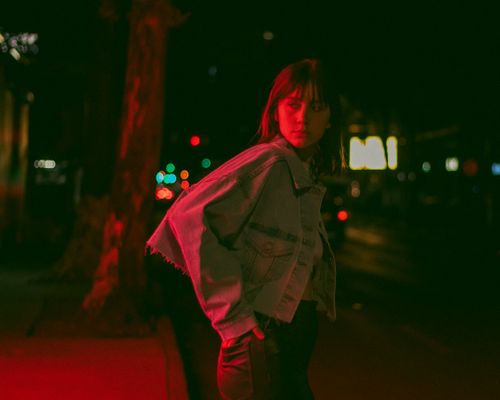 Free A young woman in a denim jacket stands on a dimly lit street at night, Ciudad de México. Stock Photo