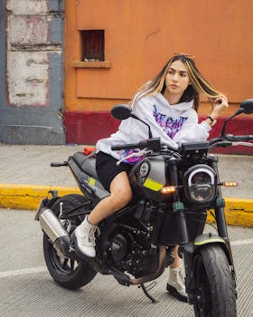 Young woman in stylish streetwear posing on a motorcycle in the vibrant streets of Mexico City.