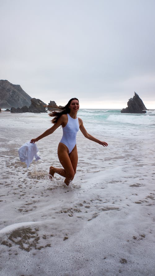 A Woman in White Swimsuit Running on the Beach