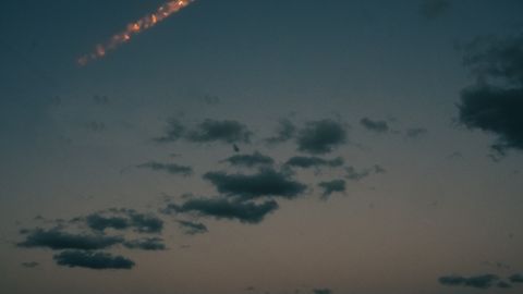 Stunning night view of a rocket launch over Cocoa Beach, Florida, showcasing a bright light trail above the ocean.