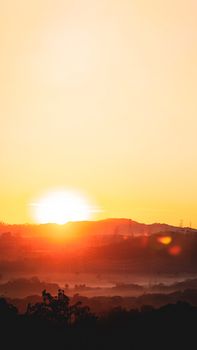 Captivating sunrise casting warm glow over misty hills and clear sky.