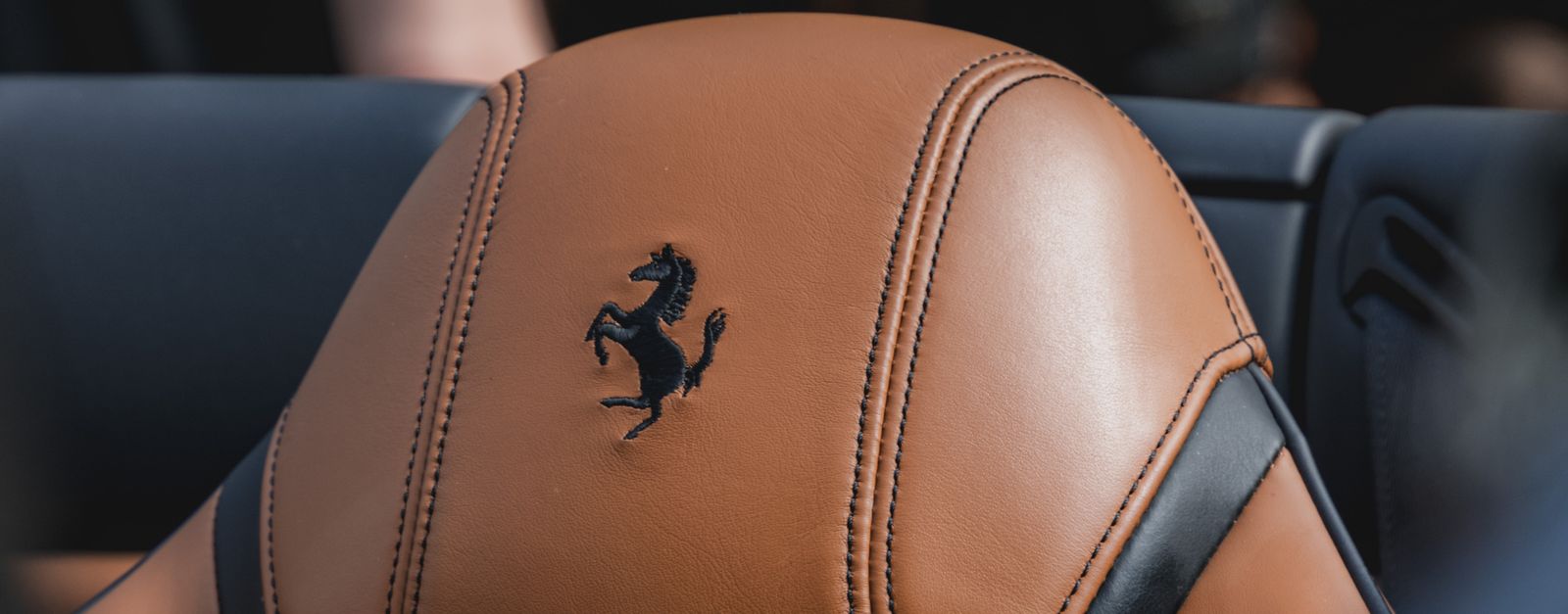 Close-up of a luxurious tan leather car seat with branding in focus.