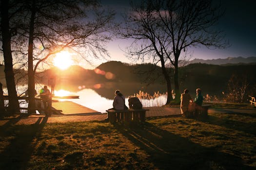 Tranquil scene of people relaxing by a lake during sunset at a scenic park.