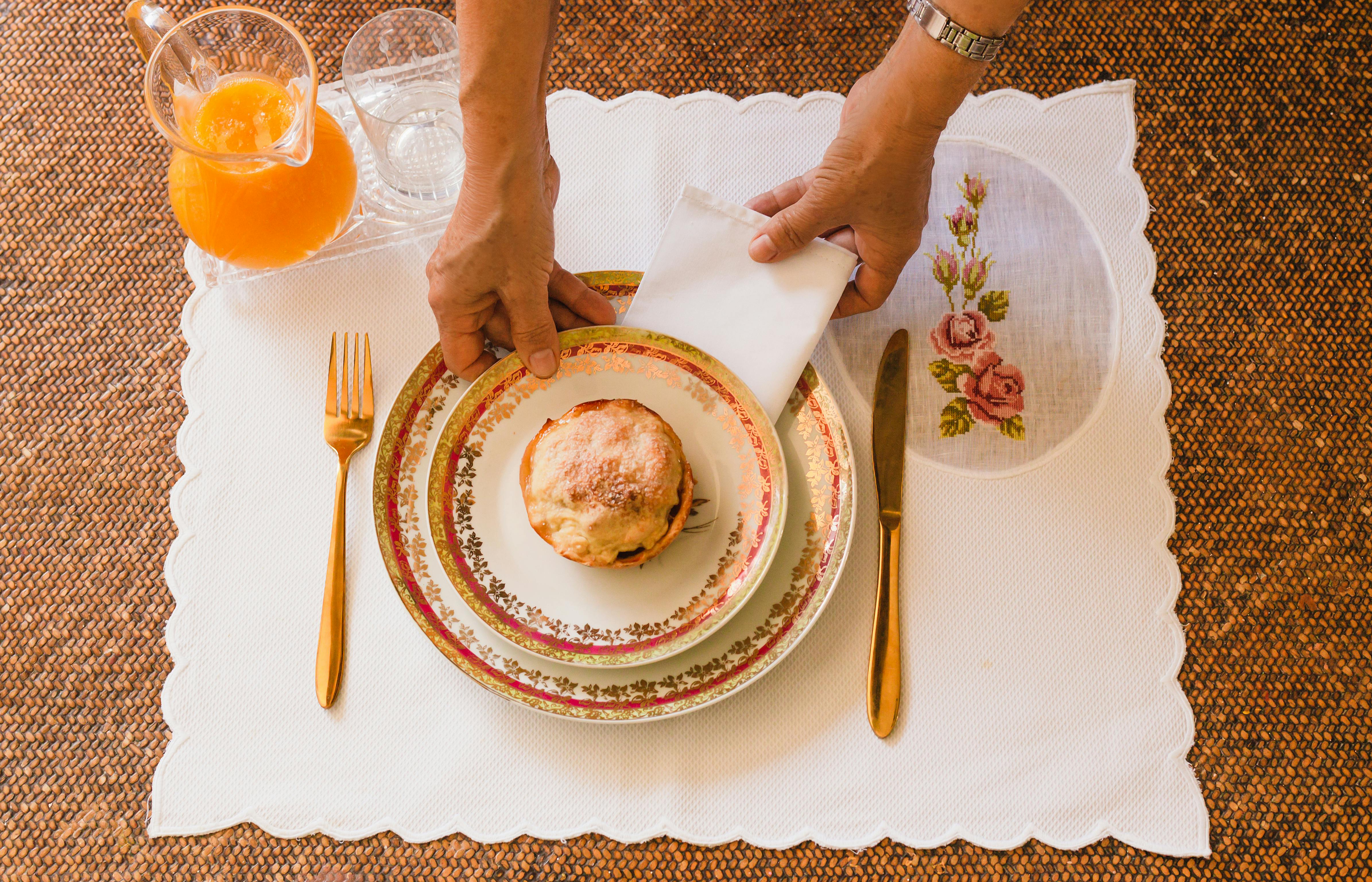 Top view of a breakfast table setup in Salvador, Brazil with floral plates and orange juice.