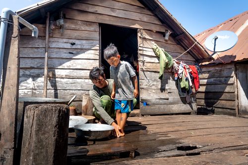 Free A father and son share a bonding moment while washing on a rustic wooden porch under clear skies. Stock Photo