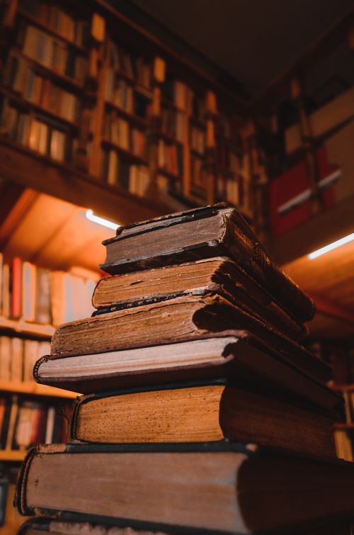 Free Close-up of stacked vintage books in a warm, dimly lit library, emphasizing a nostalgic atmosphere. Stock Photo