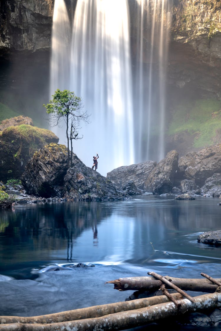 Person Standing On Rock Near Waterfall