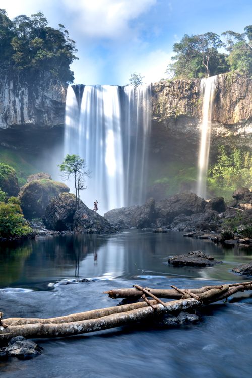 Free Stunning waterfall cascades into calm pool surrounded by lush greenery. Stock Photo