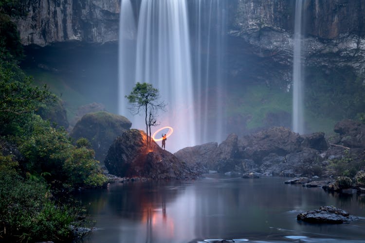 Person Standing On Rock Near Waterfall Painting With Light