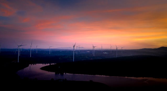 A row of wind turbines at sunset showcasing renewable energy against a vibrant sky.