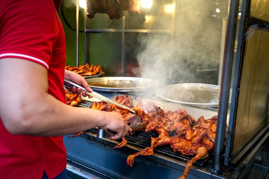 Street vendor grilling marinated chicken wings over open flame, creating a smoky flavor.