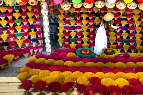 Free A vibrant display of incense sticks with a woman in traditional attire at a Vietnamese market. Stock Photo