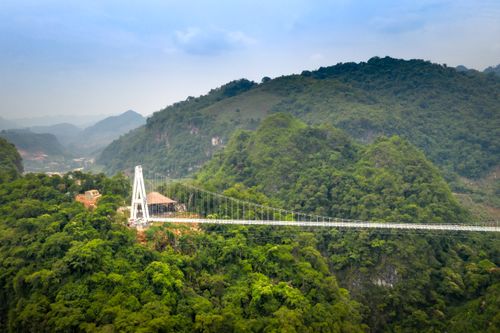 Free A stunning suspension bridge stretches across a verdant valley surrounded by mountains. Stock Photo