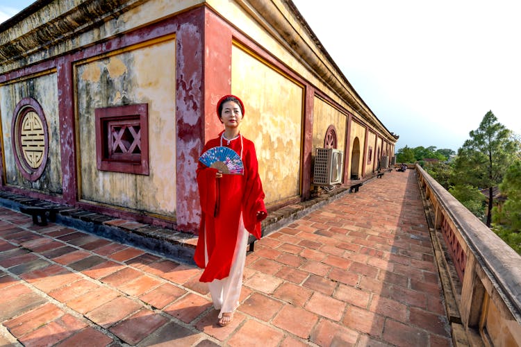 Woman In Red Ao Dai Standing In Front Of House