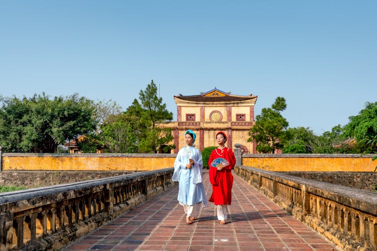 Women In Vibrant Ao Dai Walking On Bridge