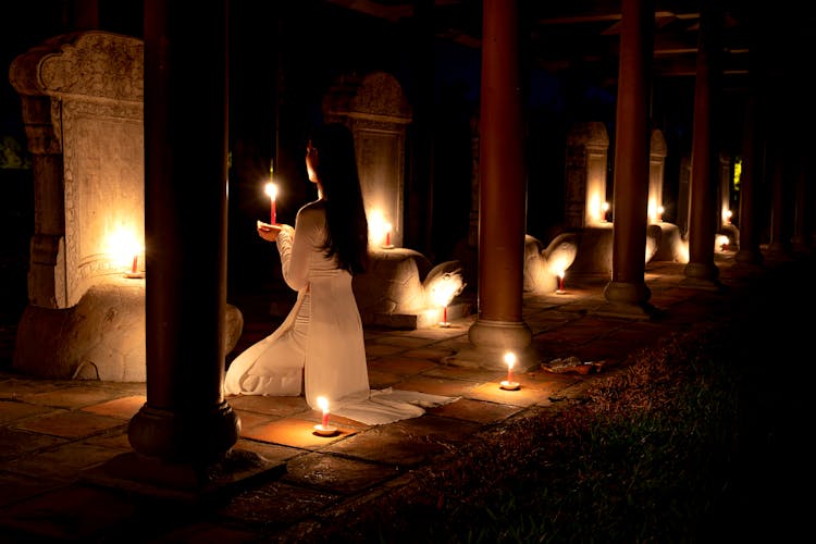 Woman With Candle Praying In Dark Temple