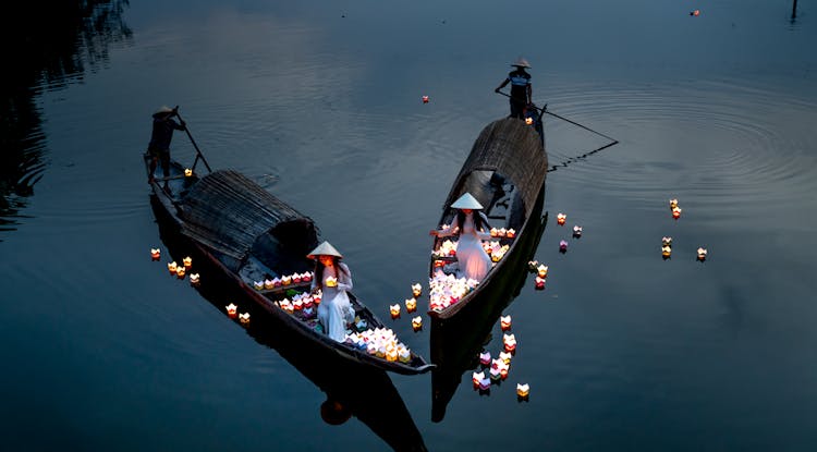 High Angle Shot Of Women On Boats Decorating Pond With Lanterns At Dusk