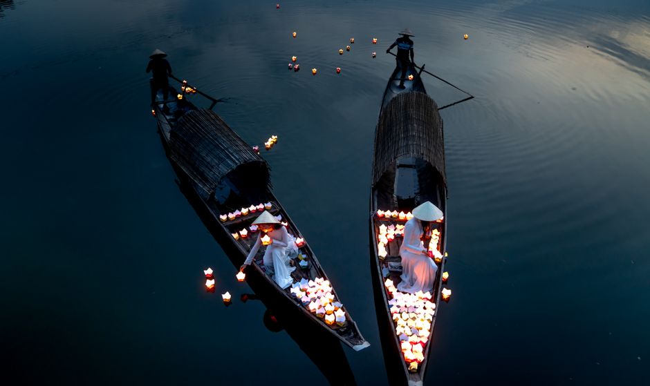 Peaceful scene of lantern-filled boats on a river at Hoi An Lantern Festival.