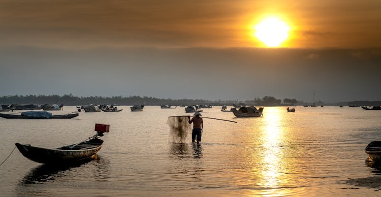 Fisherman Standing In The Water And Holding A Net