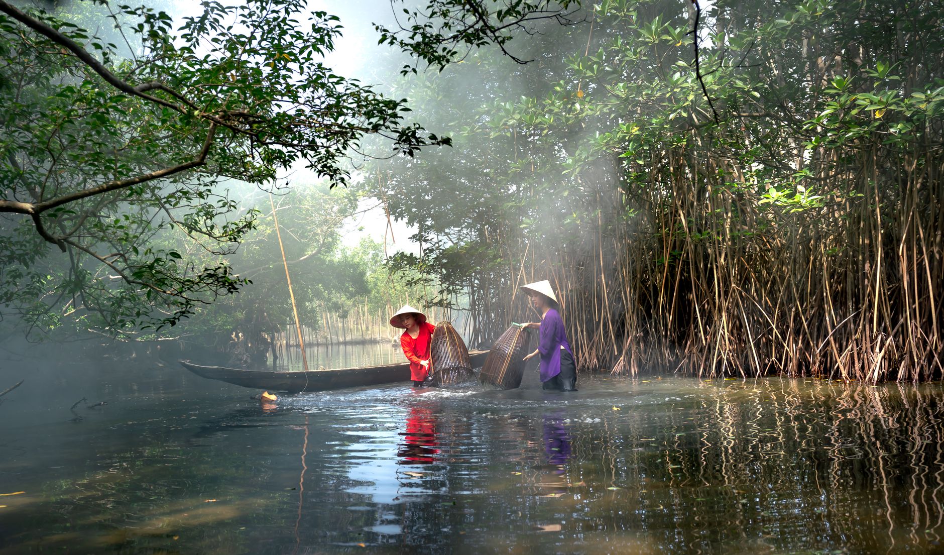 Two women fishing in a serene mangrove forest using traditional methods.