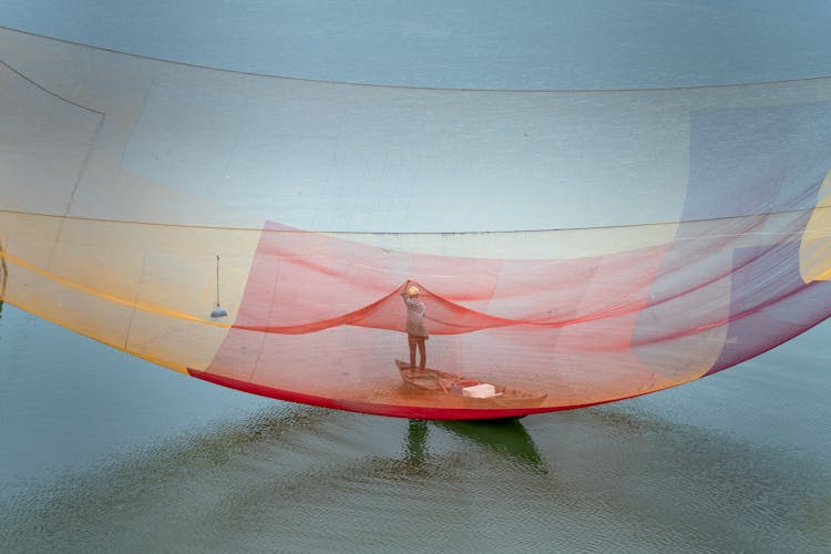 Fisherman Standing In The Boat And Hanging Up Fishing Nets 