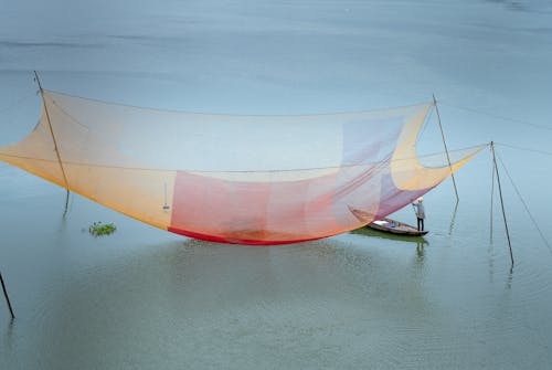 Person Standing on Boat Beside a Fishing Net