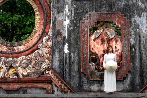 Woman in White Traditional Dress  Standing Beside a Shrine