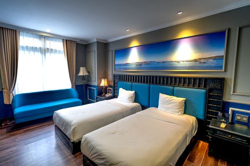 Free Luxurious hotel room features twin beds, modern decor, and ambient lighting. Stock Photo