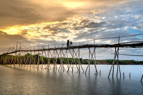 A Person with a Bicycle Crossing a Wooden Footbridge