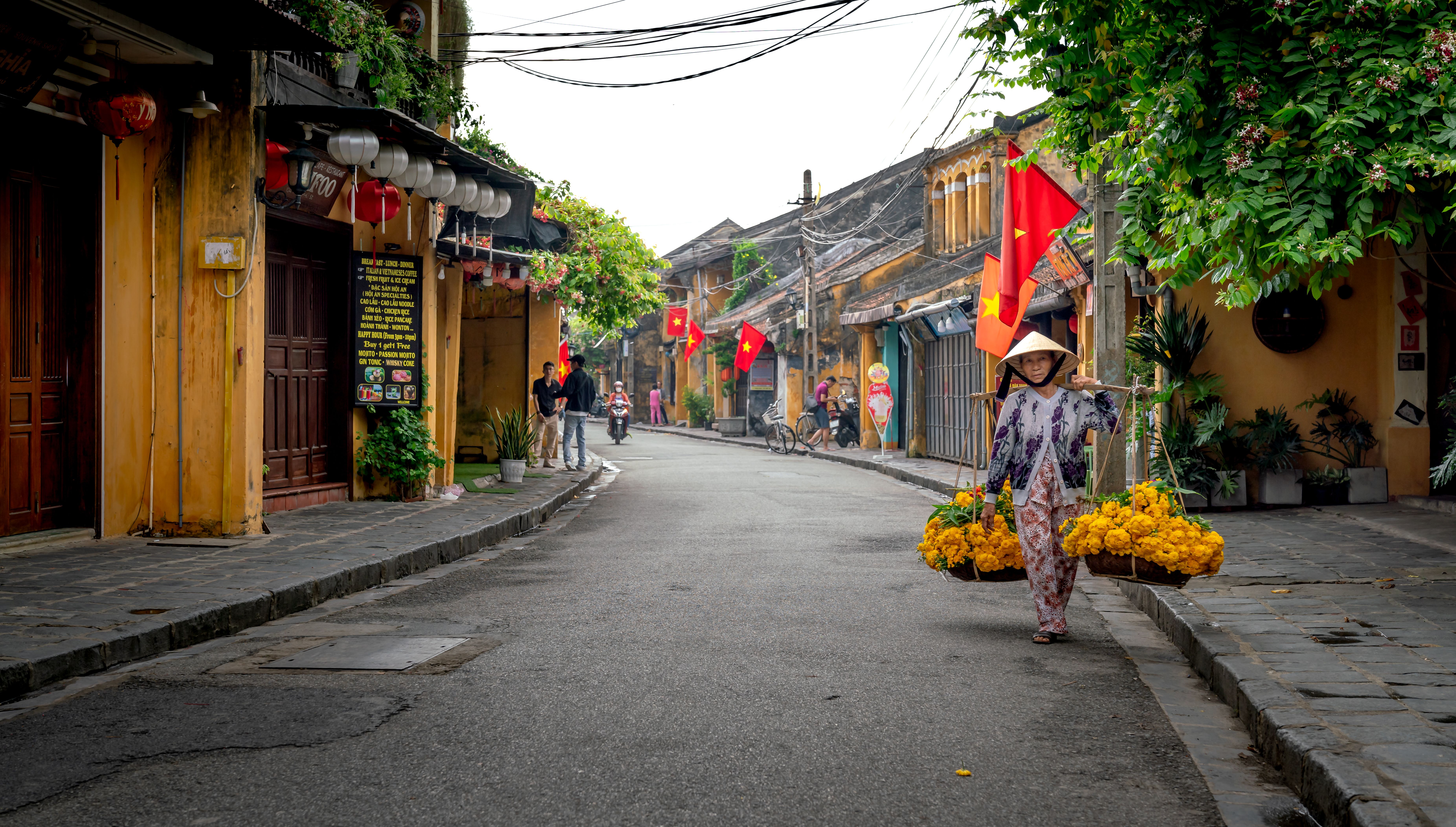 A vibrant street scene in Vietnam featuring a woman carrying flowers in Ho Chi Minh City.