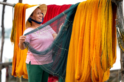 An Asian woman smiling while handling colorful fishing nets outdoors.