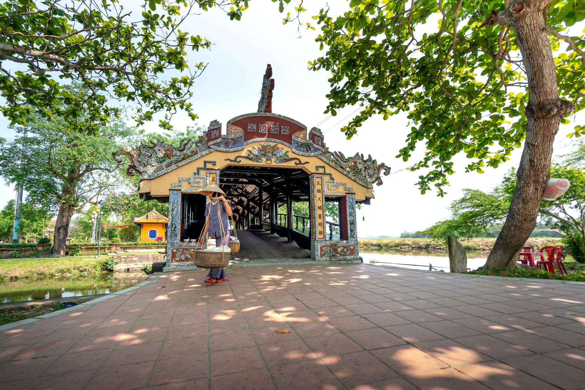 Thanh Toan Bridge in Vietnam, an iconic historical landmark, surrounded by vibrant green trees.