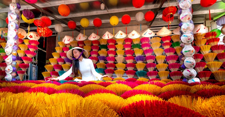 Woman Selling Conical Hats And Colorful Incense Sticks