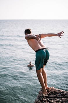 Man Standing on Cliff Near Sea · Free Stock Photo