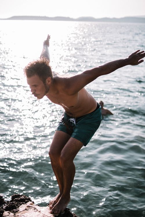 Free A young man prepares to dive into the sparkling ocean on a sunny day, enjoying outdoor fun. Stock Photo