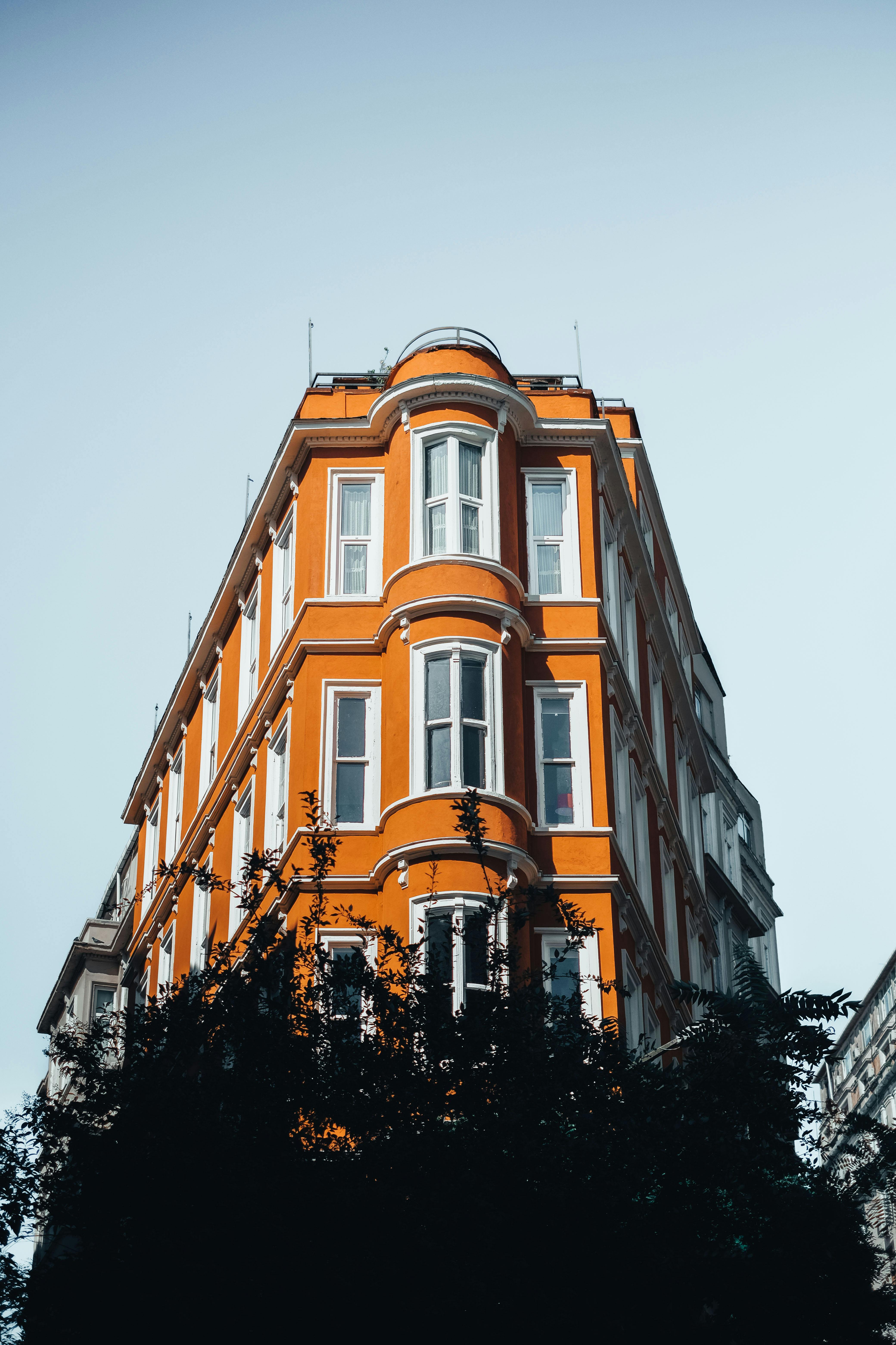Free Vibrant orange building facade against a clear blue sky, capturing urban architecture. Stock Photo