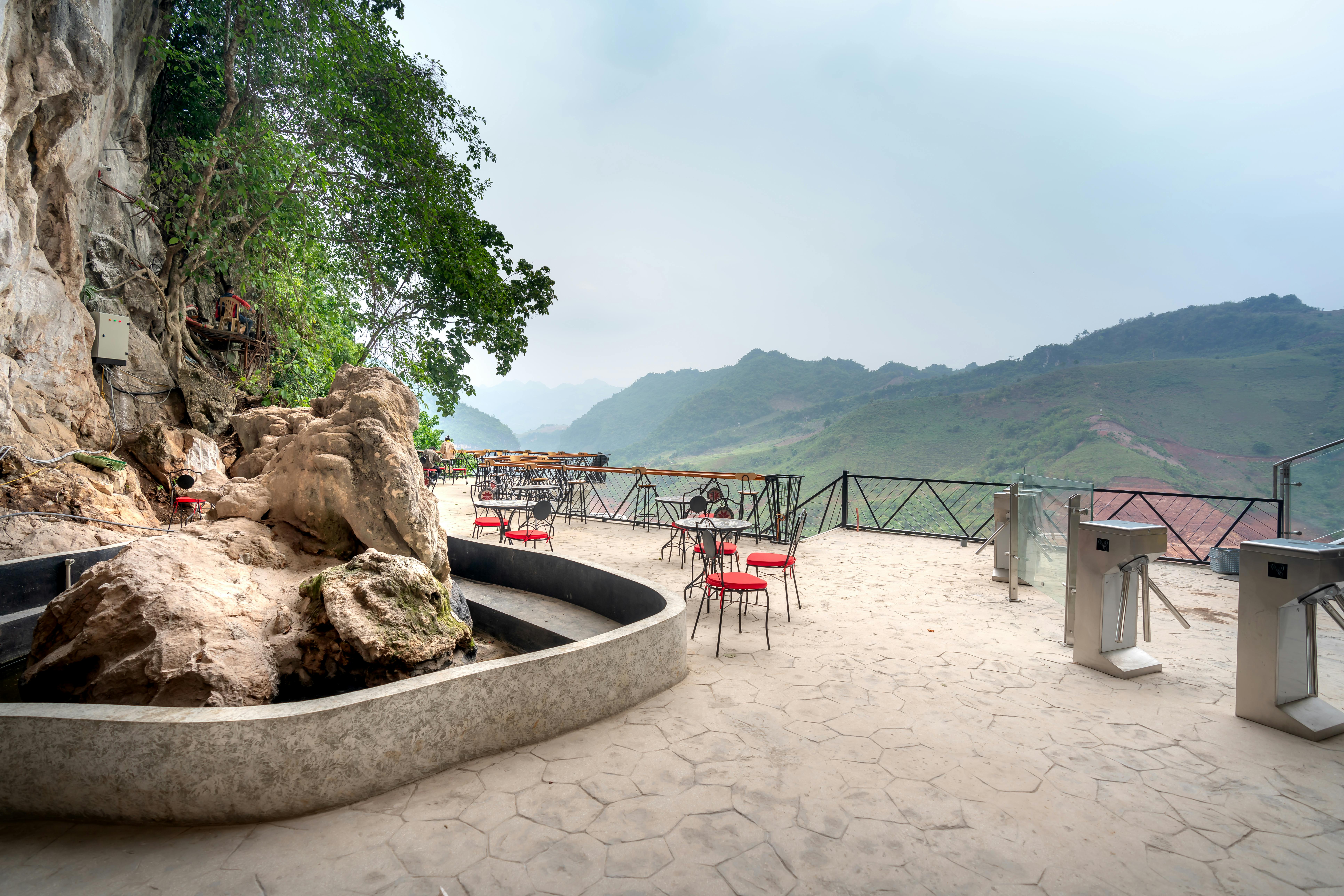 Outdoor cafe terrace with red chairs overlooking mountains and rocky landscape