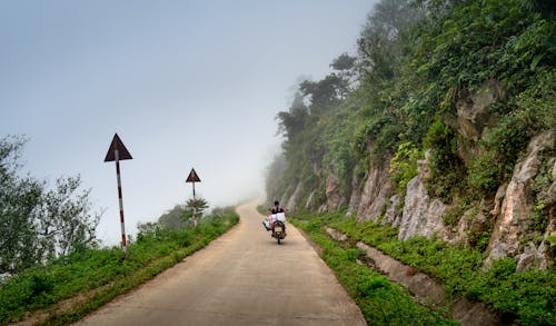 Person Riding a Motorcycle on a Road Near a Cliff