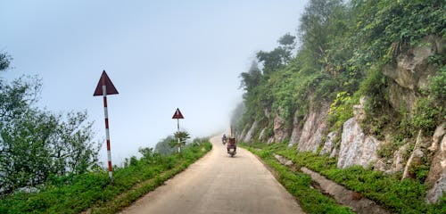 A Person Riding Motorcycle on Road near the Mountain