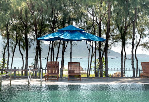 Blue Parasol and Wooden Pool Chairs at Poolside