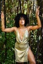 身着金色连衣裙的优雅女子在竹林间摆姿势，展示风格和时尚