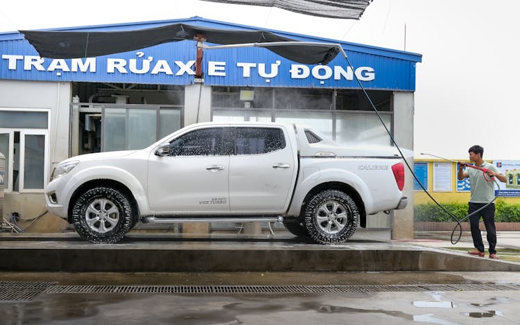 Man Spray Washing A Pickup Truck