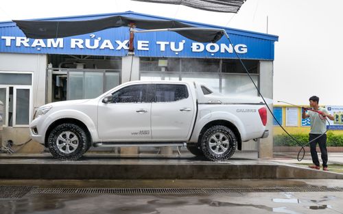 Free Adult using pressure washer to clean a white pickup truck at an outdoor car wash facility. Stock Photo