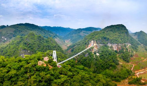 Free A breathtaking aerial view showcasing a suspension bridge amidst lush green mountains. Stock Photo