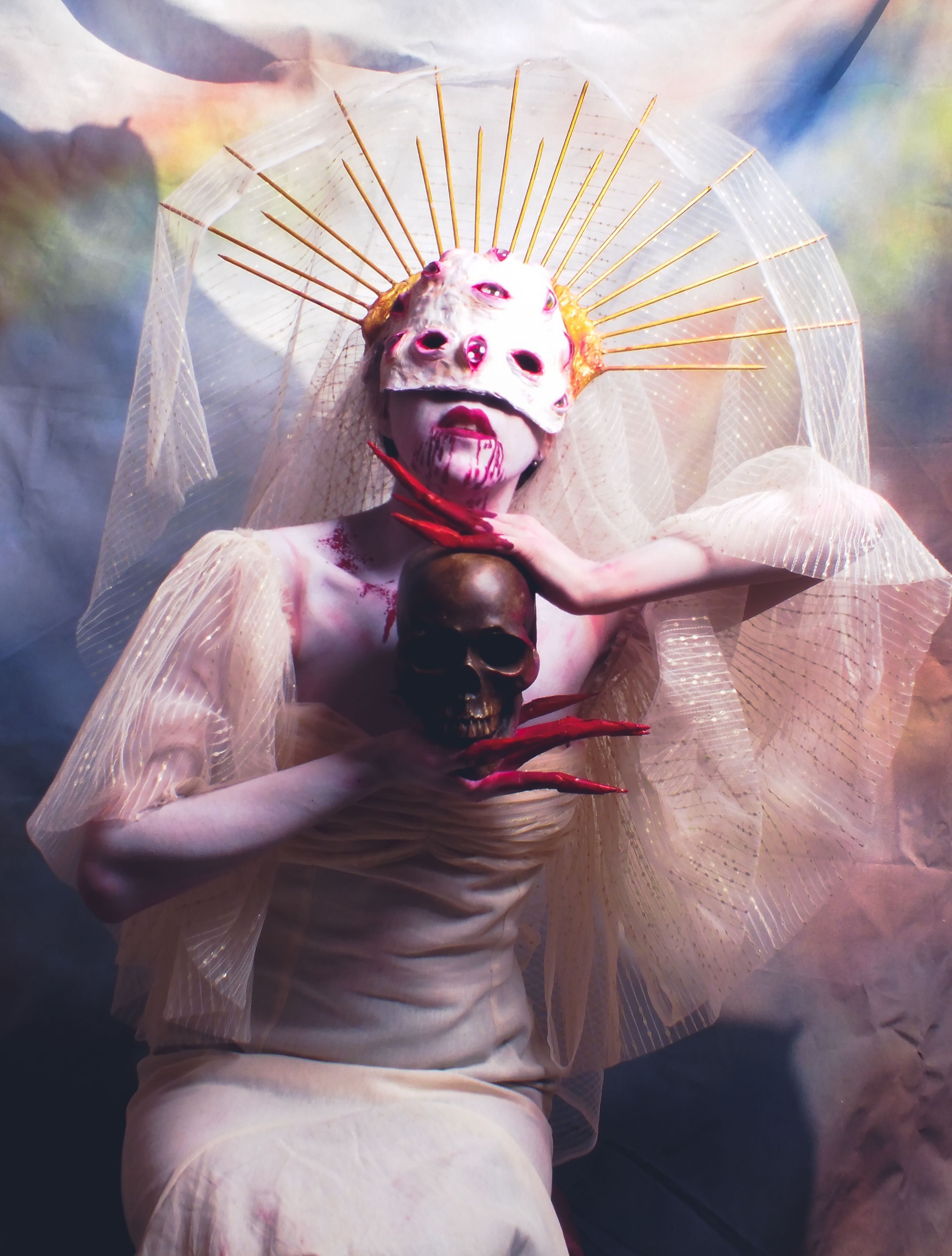 Mystical figure in costume with mask and skull, set against colorful background.