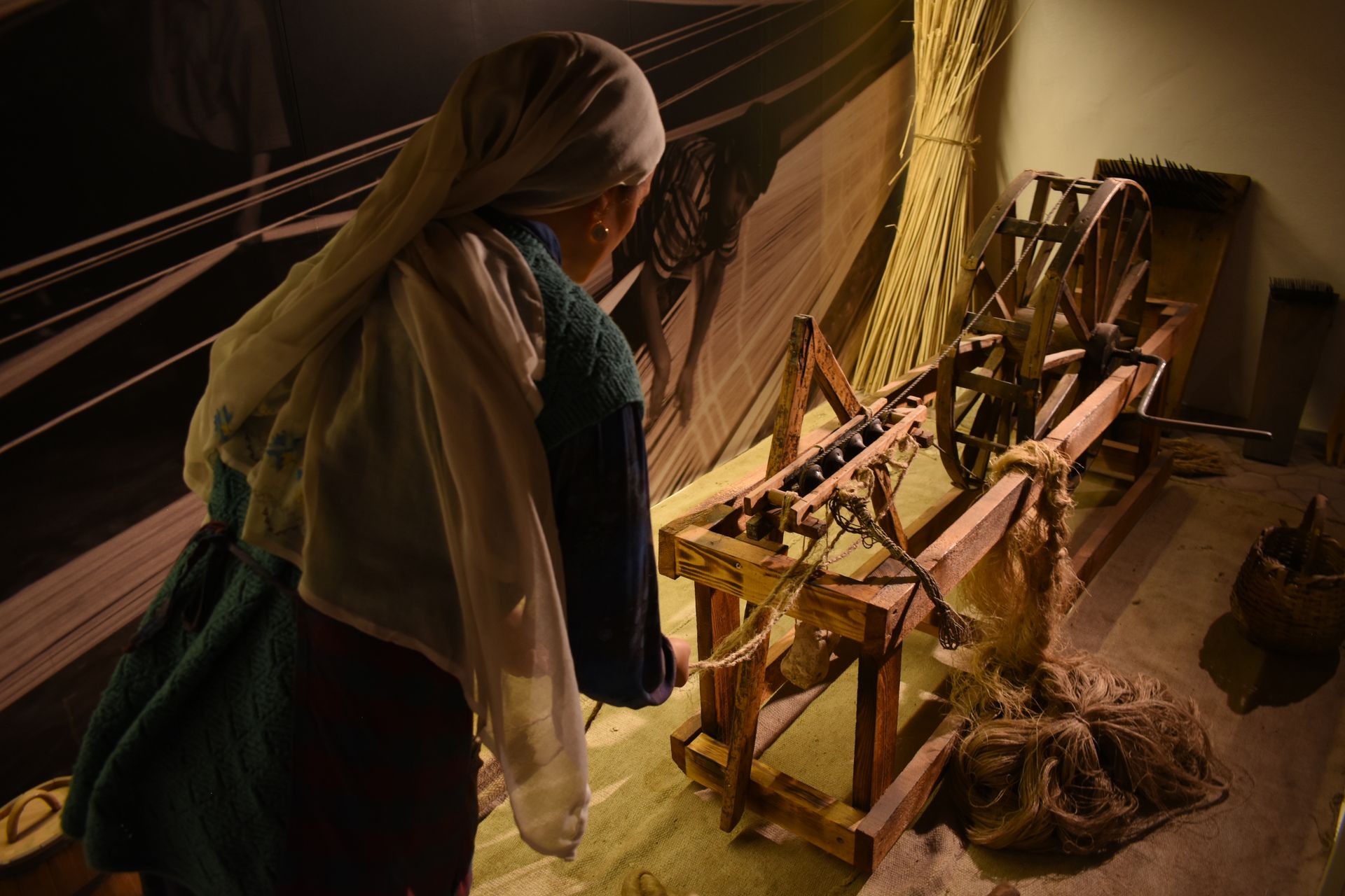 A woman operates a vintage wooden loom, showcasing traditional weaving techniques indoors.