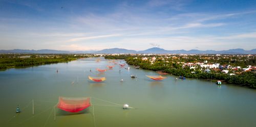 Free Stunning aerial shot of colorful fishing nets on a calm river with mountains and a village in the background. Stock Photo