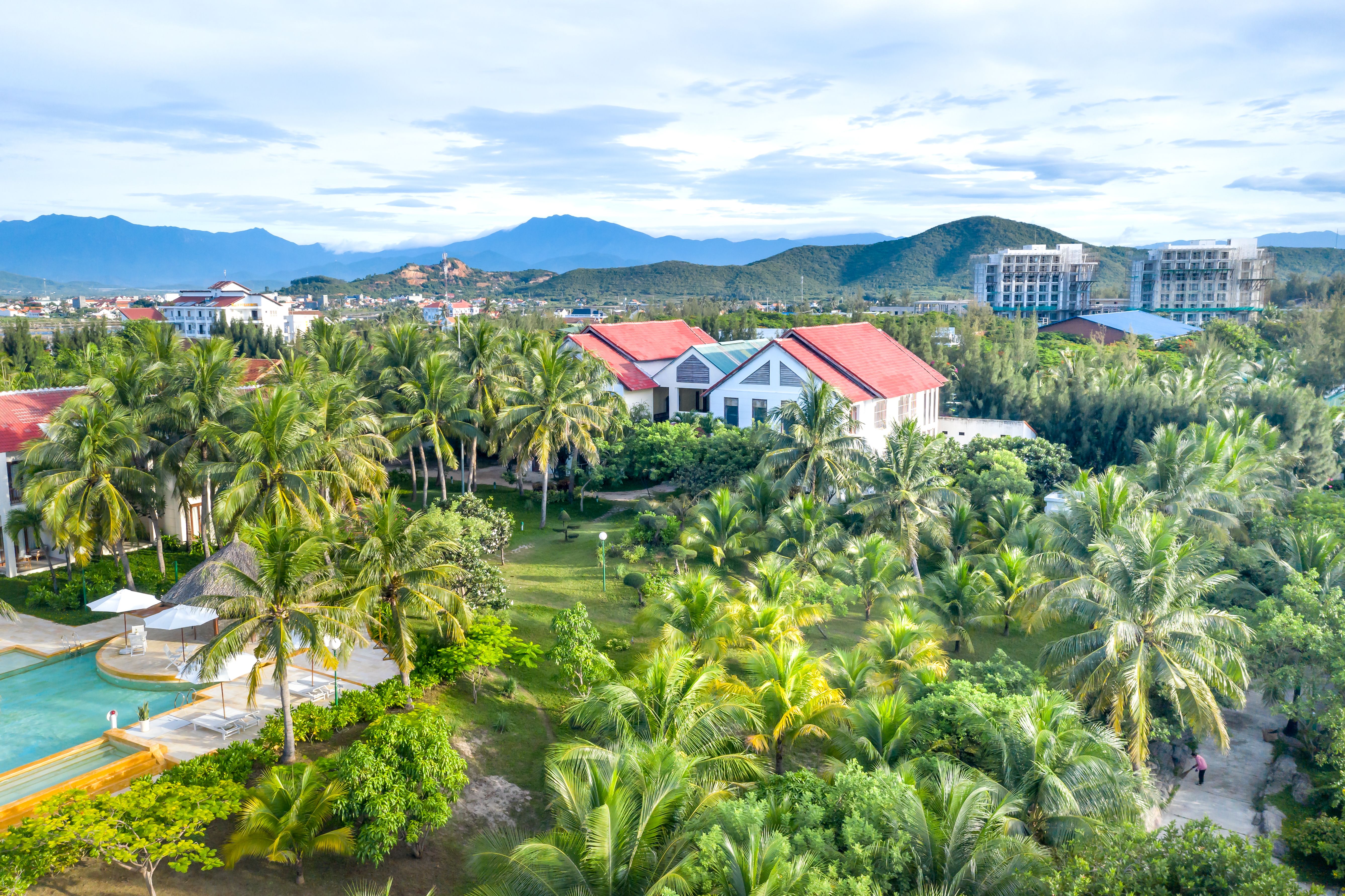 Stunning aerial view of a tropical resort surrounded by lush palm trees and mountains.