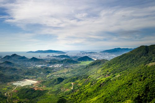 Free Breathtaking landscape view of a city nestled between lush mountains and the coastline, captured in daylight. Stock Photo